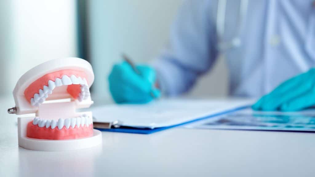 Dental model on a desk while a dentist writes up a treatment plan, illustrating how to choose a dental clinic in Turkey