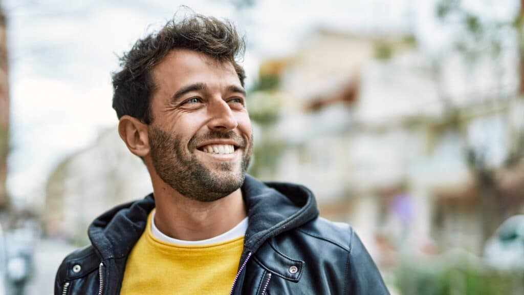 A smiling man in his thirties outdoors, illustrating a guide to hair transplant costs in the UK and Turkey