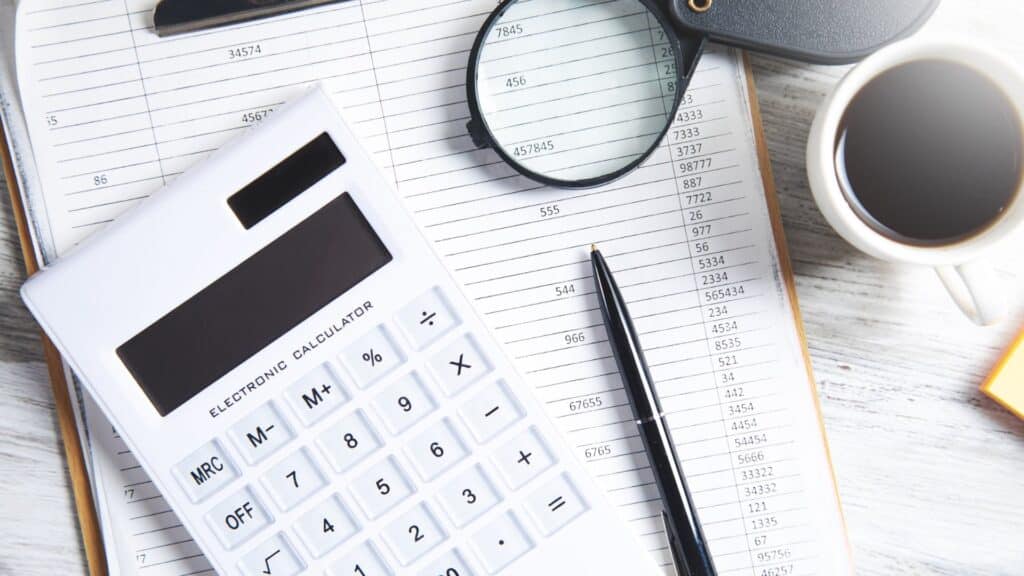 Calculator, pen and magnifying glass on a printed sheet of figures, illustrating how to compare gastric sleeve price quotes